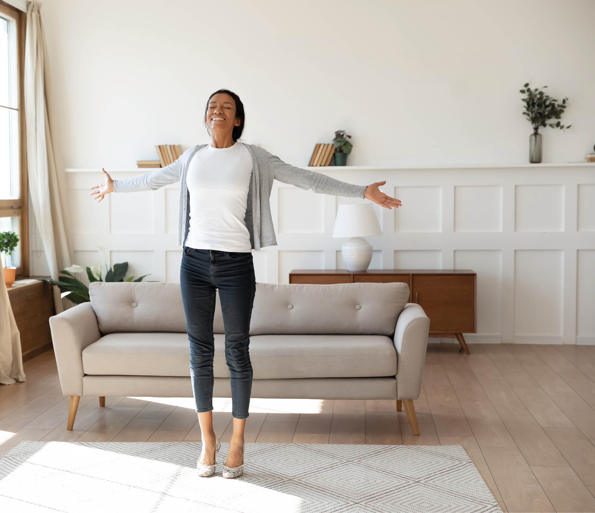 Happy African American young woman stand dance in bright modern living room meet welcome new day, overjoyed smiling biracial female feel optimistic excited, celebrating good news at home